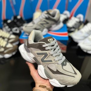TĂȘnis New Balance 9060 em tons de grafite, cinza e branco, com detalhes em tecido, camurça e couro ecolĂłgico.