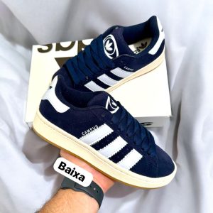 Tênis Adidas Campus 00s em camurça azul marinho com detalhes em branco e listras brancas. Solado off white com detalhe caramelo, modelo de primeira linha, ideal para treinos, passeios e looks casuais. Disponível na Maiara Valentina Moda Feminina.